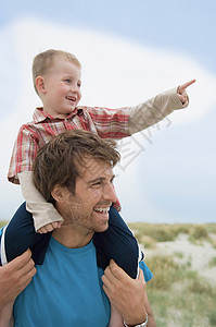 男孩在父亲的肩上指着图片