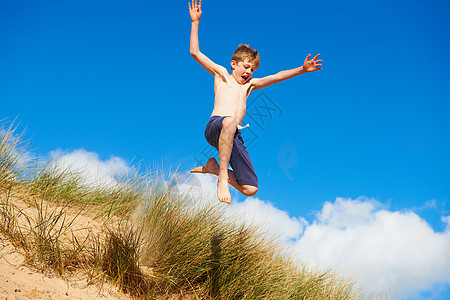 男孩在海滩上跳跃图片