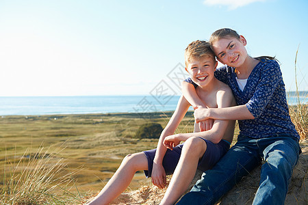 少女搂着男孩坐在海滩上图片