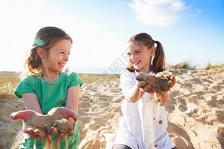 两个玩沙的女孩笑着对视图片