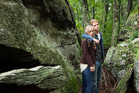 年轻的情侣站在岩石间背景图片