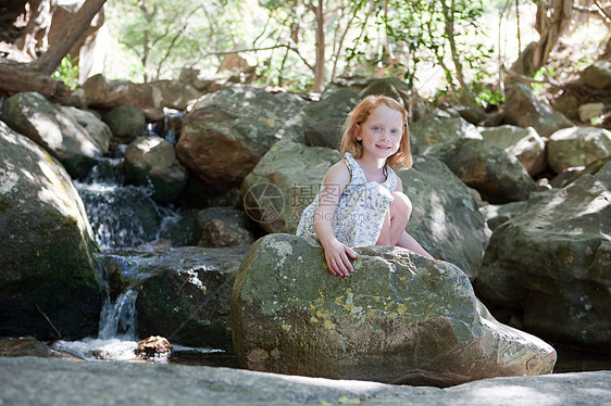 女孩坐在河边岩石上图片