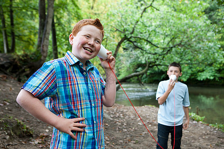 两个男孩使用纸杯和绳子在林地进行交流图片