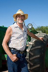 高龄农民靠着拖拉机微笑图片