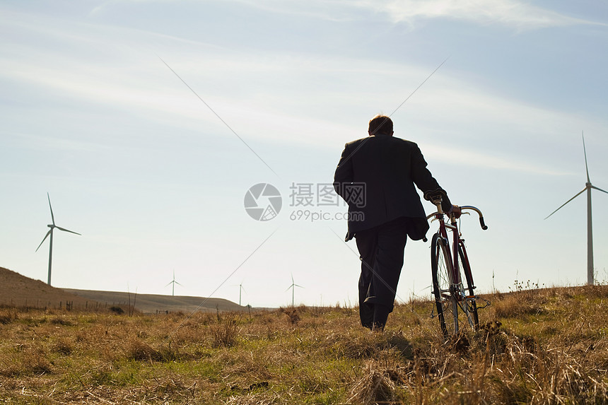 男人推着自行车在荒废的草地上走图片