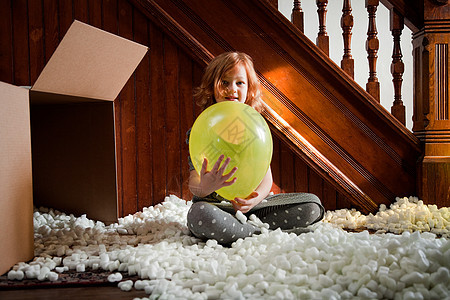 女孩玩气球和纸箱包装材料图片