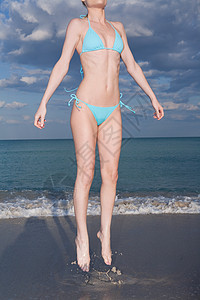 穿比基尼的中成年女子在海滩上跳跃图片