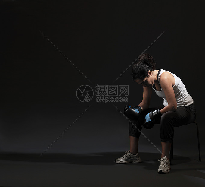 坐在黑色背景下的女拳击手图片
