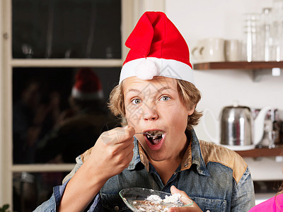 穿圣诞帽子吃蛋糕的十几岁男孩肖像图片