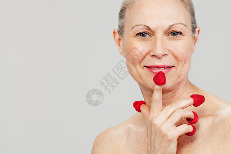 指尖上戴着草莓微笑的中年妇女图片