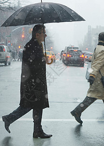 成年男子在雨中穿越城市街道图片