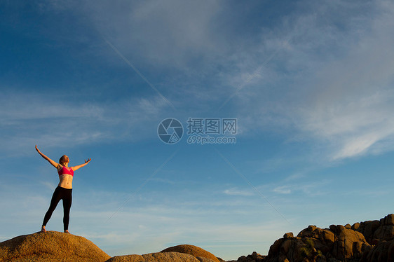 站在沙漠中双臂张开的年轻女孩图片