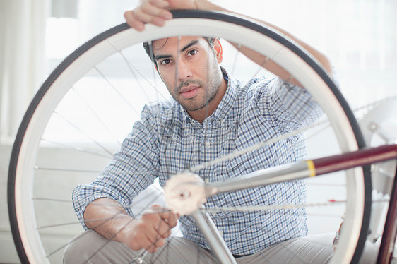 男子在室内修理自行车轮图片