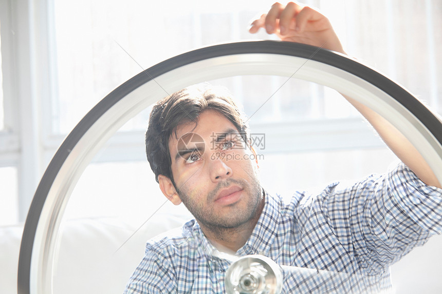 男子在室内修理自行车轮图片
