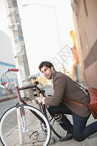 在街上锁单车的男子图片