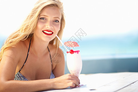 穿着比基尼在户外喝热带饮料的年轻女性图片
