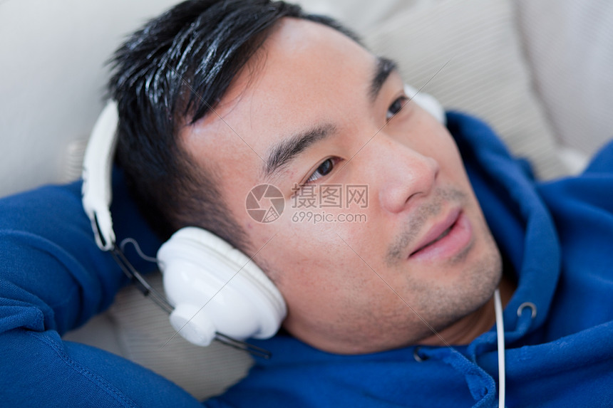 躺在在沙发上戴着耳机的男性图片