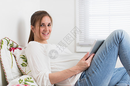 携带数字平板电脑的床上孕妇肖像图片