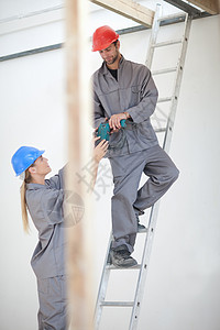 在建筑工地从事电钻的男女工人图片