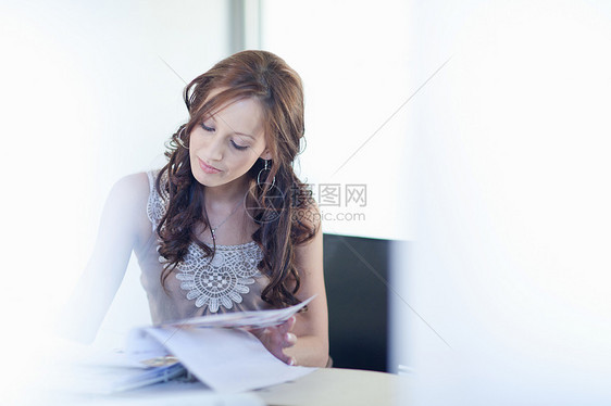 年轻女人坐在书桌上写作图片