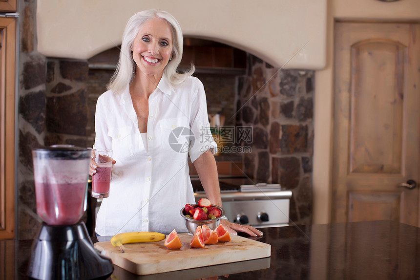 年长的妇女在厨房做果汁图片