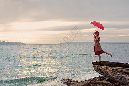 海边悬崖上撑着雨伞的女性图片