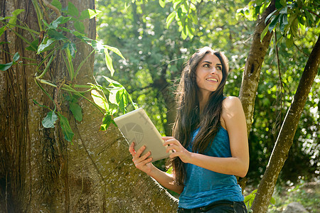 在丛林使用平板电脑的年轻女性图片
