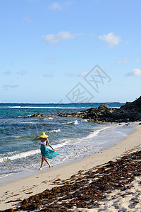 年轻女性在热带海滩上行走图片