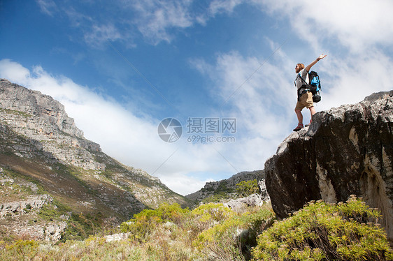 男徒步站在岩石的上手臂伸展图片