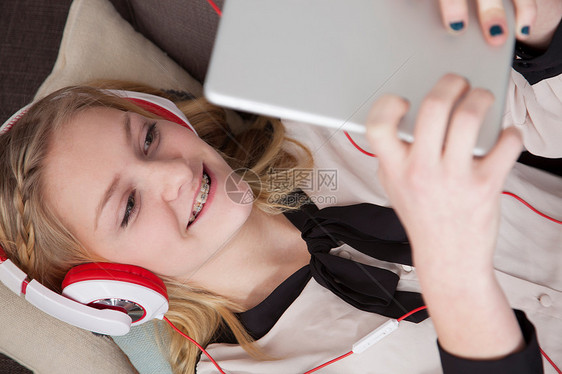 女孩用数字平板电脑躺在沙发上图片