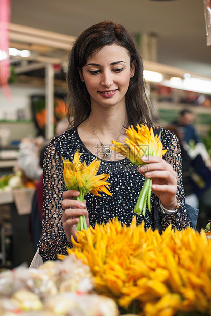在市场上选择黄色花的女性图片