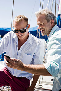 两个男人在游艇上看智能手机图片