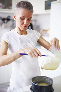妇女将蛋糕混合物倒入碗里图片