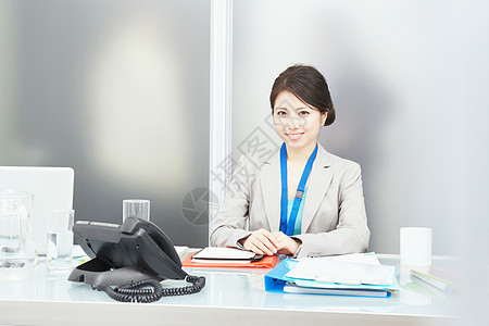 女人坐在办公桌上微笑图片