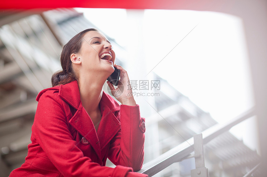 在购物商场用手机打电话的年轻妇女图片