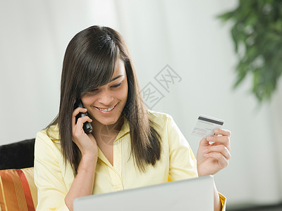 拿着信用卡打电话的女人图片