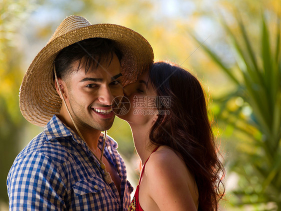 年轻女子亲吻戴太阳帽微笑的图片