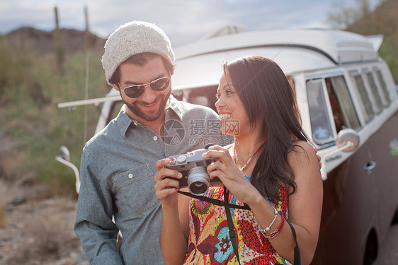 年轻女子带着照相机与男朋友在路上旅行图片