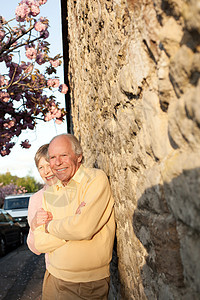丈夫和妻子靠在石墙上微笑图片