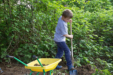 男孩户外玩耍使用铲子挖土图片