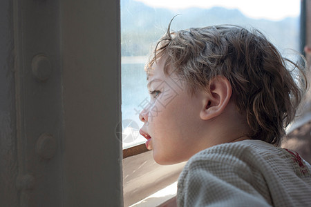 年轻男孩从渡轮窗外看图片