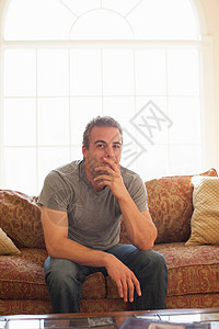 手撑着下巴坐在沙发上的男人图片