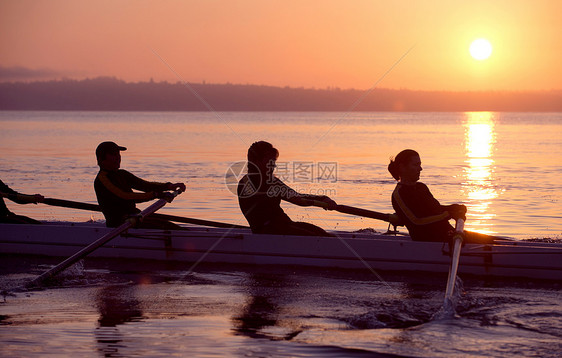 日落时划船的人图片