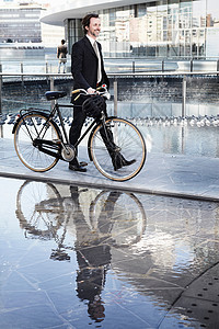 城市中扶着自行车行走的商务男性图片