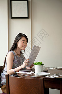 在餐馆看菜单的年轻女性图片