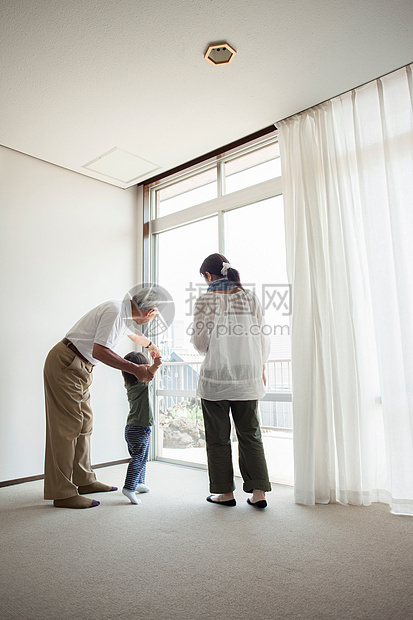 爷爷和小孙子站在窗口旁玩耍图片