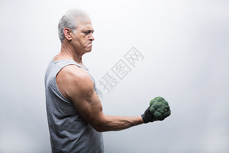 穿运动服的退休老人手举花椰菜图片