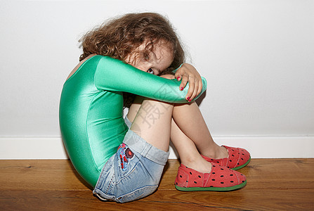 抱着双腿坐在地板上的小女孩图片素材