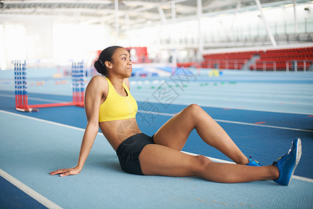 青年女运动员坐在地板上休息图片