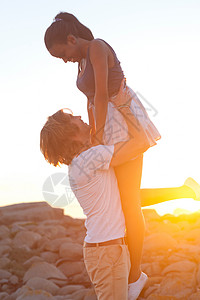 日落时年轻男人托起女朋友图片素材